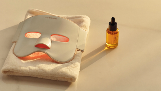 Premium LED light therapy face mask and copper peptide serum on warm marble in soft golden light